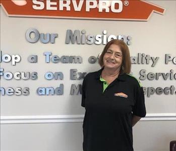 Lady smiling in front of Servpro logo sign