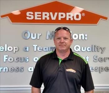 Man standing in front of SERVPRO logo with green and black polo shirt